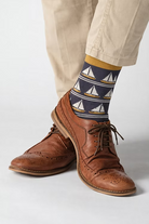 Person wearing brown leather shoes and socks with sailboat pattern.