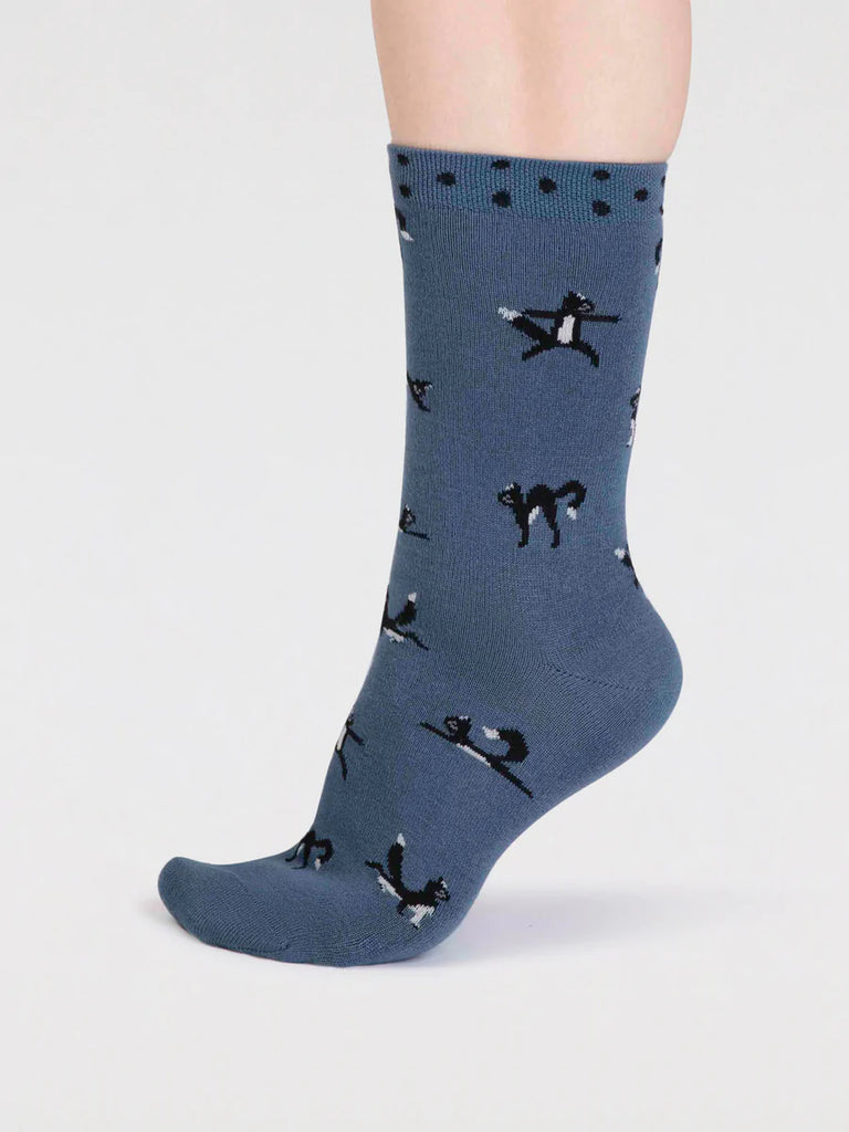 Side view of misty blue bamboo and cotton socks with a black cat in yoga positions print and black spots around the cuff
