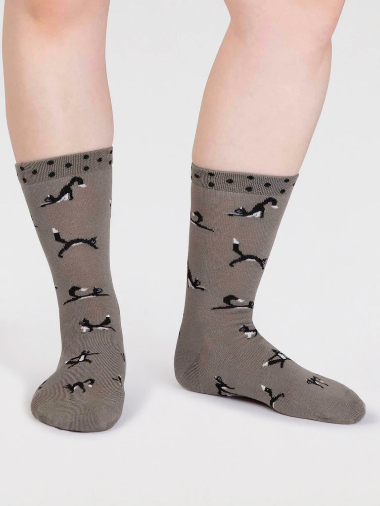 Pea green bamboo and cotton socks with a black cat in yoga positions print and black spots around the cuff