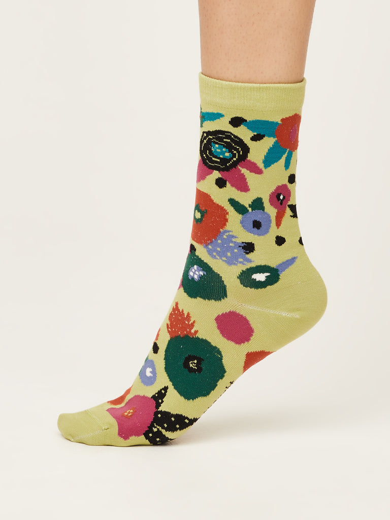 Side view of abstract floral super soft premium quality organic socks in pea green with green orange red blue and black flower design.