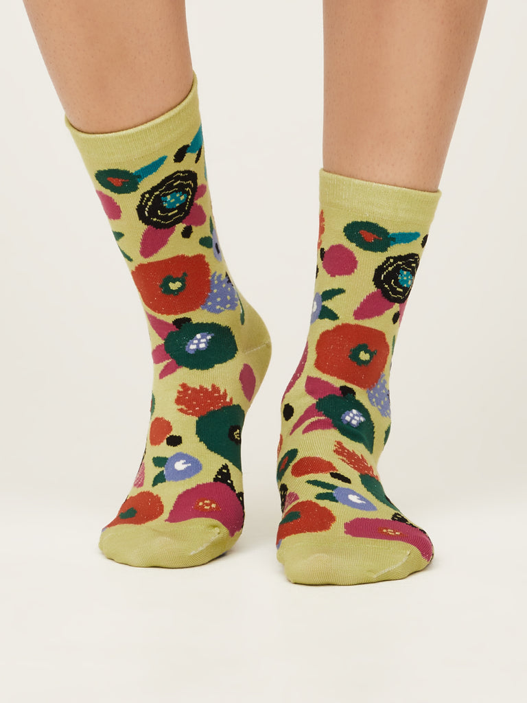 Front view of abstract floral super soft premium quality organic socks in pea green with green orange red blue and black flower design.