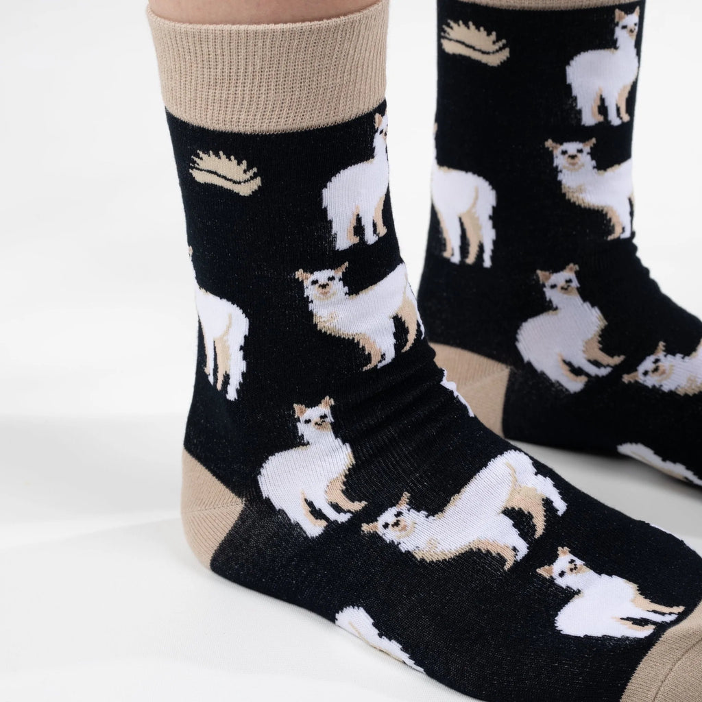 Front on view of model in super soft premium quality bamboo socks with a beige and white Alpaca print on a black background 