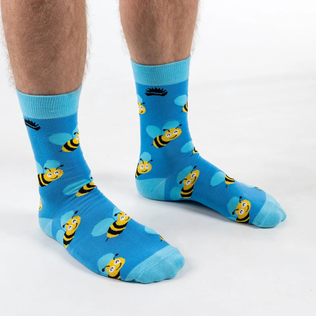 Front on view of model in super soft premium quality bamboo socks featuring a yellow bee with blue wings design on a vibrant blue background