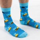 Front on view of model in super soft premium quality bamboo socks featuring a yellow bee with blue wings design on a vibrant blue background