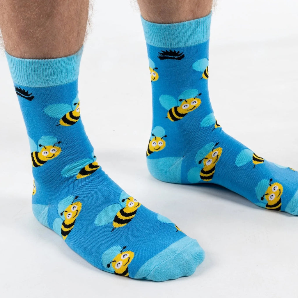 Front on view of model in super soft premium quality bamboo socks featuring a yellow bee with blue wings design on a vibrant blue background