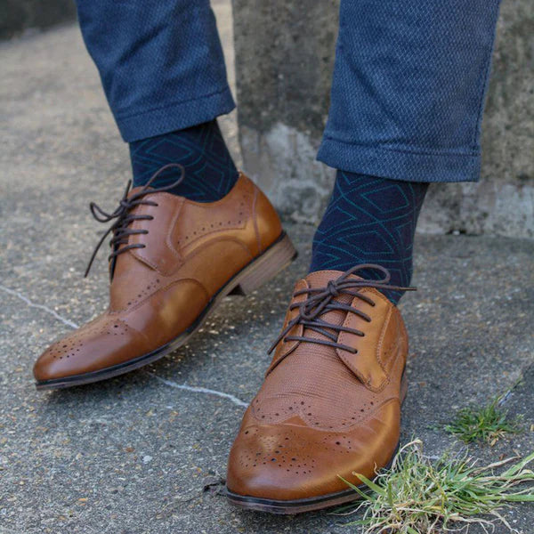 Brown shoes, navy diamond socks with green pattern by swole panda and navy trousers.
